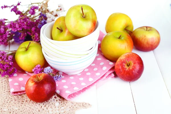 Saftiga äpplen på plattan på vita träbord — Stockfoto