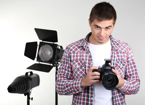 Handsome photographer with camera, on photo studio background — Stock Photo, Image