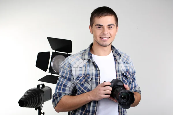 Fotógrafo bonito com câmera, no fundo do estúdio de fotografia — Fotografia de Stock