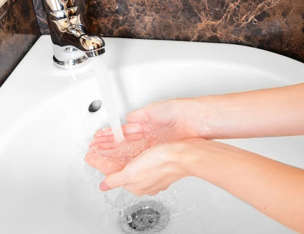 Nahaufnahme menschlicher Hände, die im Badezimmer unter dem Wasserhahn gewaschen werden — Stockfoto