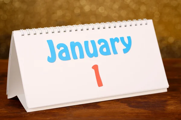 Calendário de ano novo na mesa de madeira, no fundo dourado brilhante — Fotografia de Stock