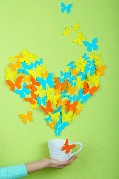 Farfalle di carta volare fuori di tazza su sfondo muro verde — Foto Stock