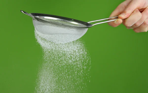 Sieve and powdered sugar on green background — Stock Photo, Image