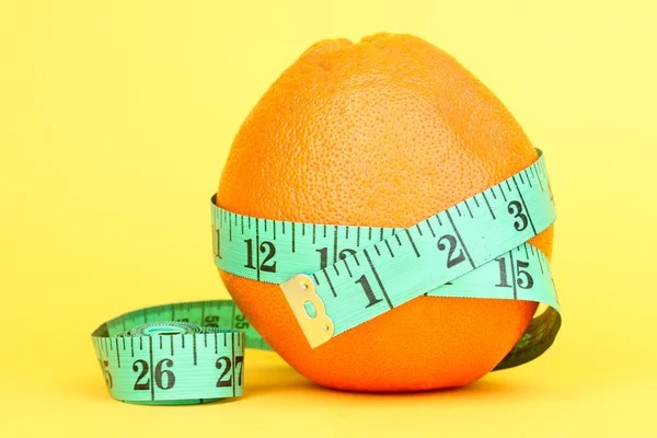 Naranja con cinta métrica sobre fondo amarillo —  Fotos de Stock