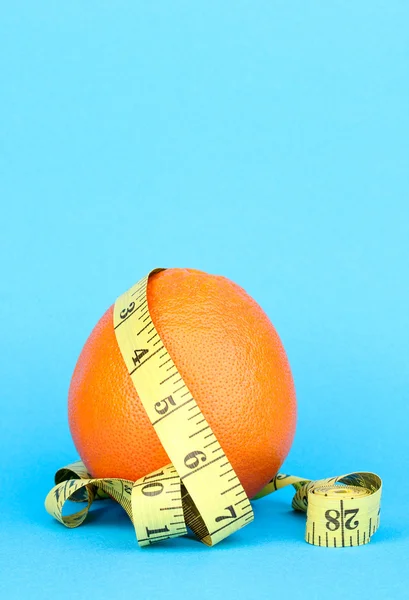 Orange mit Maßband auf blauem Hintergrund — Stockfoto