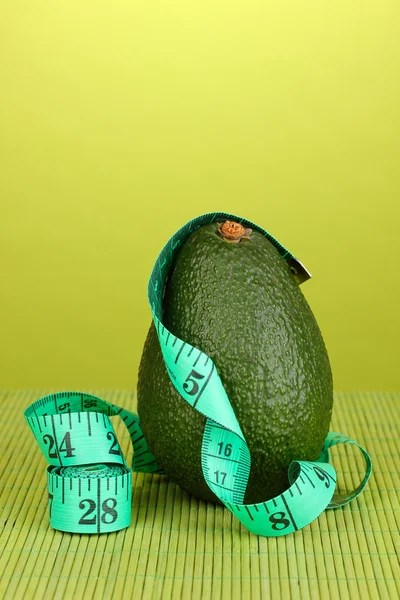 Avocado mit Maßband auf grünem Hintergrund — Stockfoto