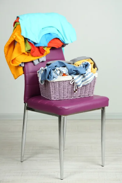 Heap of clothes on color chair, on gray background — Stock Photo, Image