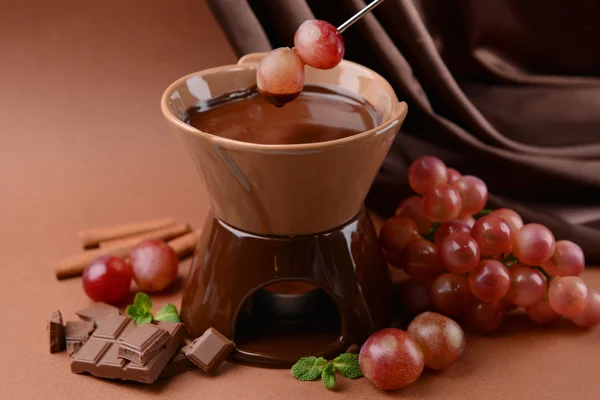 Schokoladenfondue mit Früchten, auf braunem Hintergrund — Stockfoto