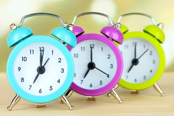 Colorful alarm clocks on table on light background — Stock Photo, Image