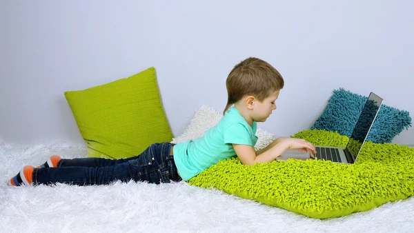 Niño pequeño con portátil en la cama — Foto de Stock