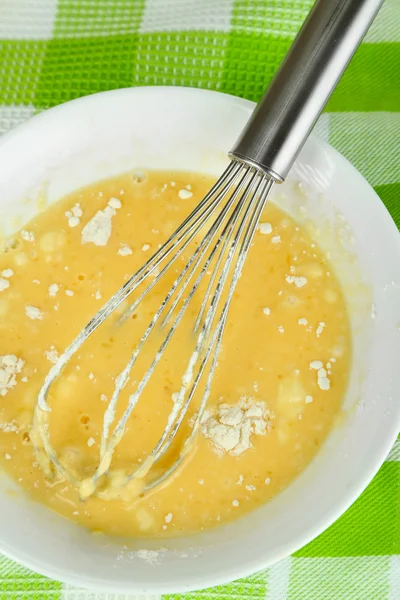 Corolla and broken eggs with flour in bowl on tablecloth close-up — Stock Photo, Image