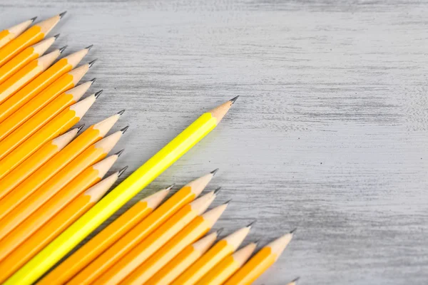 Festbleistift zwischen den üblichen Bleistiften, auf farbigem Hintergrund — Stockfoto