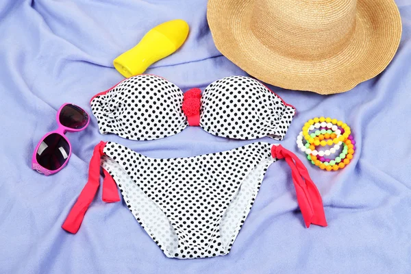 Swimsuit and beach items on purple background — Stock Photo, Image