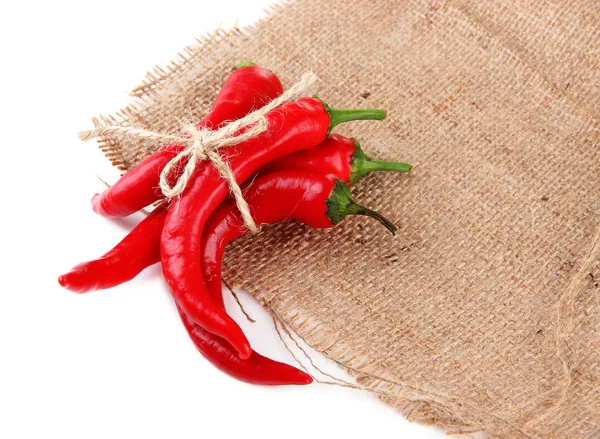 Pimentos de pimenta vermelha em pano de saco, isolados em branco — Fotografia de Stock