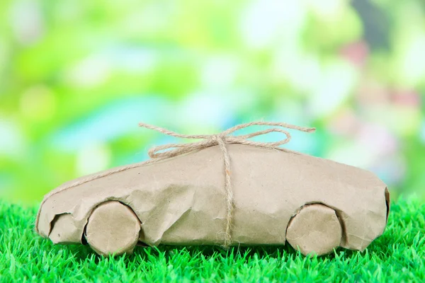 Car wrapped in brown kraft paper, on green grass, on nature background — Stock Photo, Image