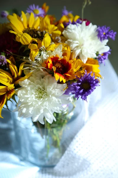 Buquê de flores silvestres em vaso de vidro no guardanapo em fundo cinza — Fotografia de Stock