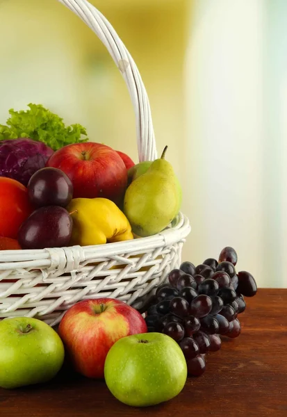 Different vegetables and fruits in basket on table on bright background — Stock Photo, Image