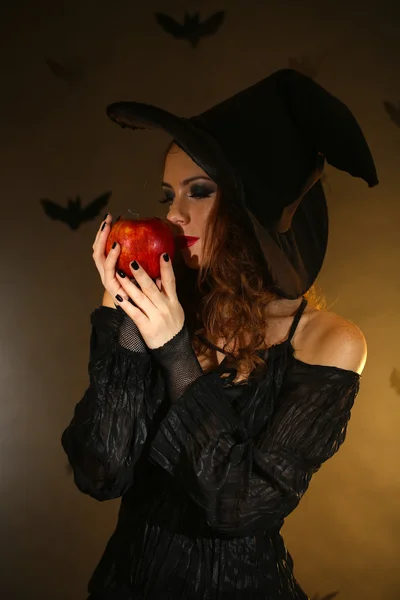 Strega di Halloween con mela su sfondo scuro — Foto Stock