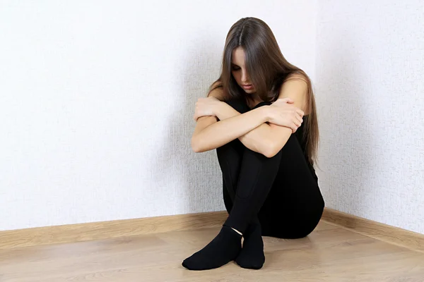 Одинокая грустная женщина, сидящая на полу у стены — стоковое фото