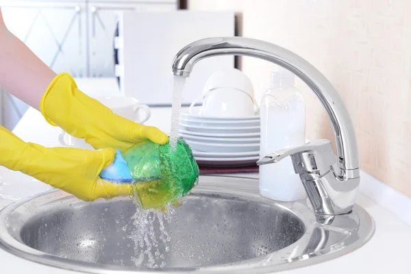 Fermer les mains de la femme qui lave la vaisselle dans la cuisine — Photo