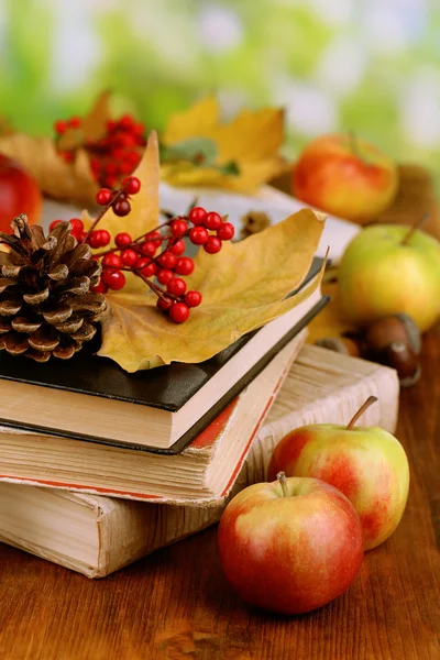 Knihy a na podzim listí na dřevěný stůl na přírodní pozadí — Stock fotografie