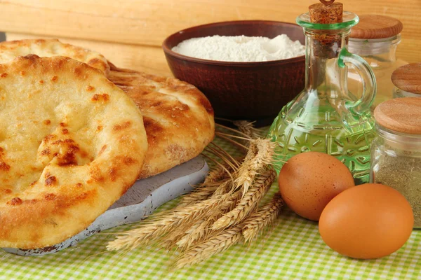 Pita breads on wooden stand with spices and spikes on tablecloth on wooden background — Stock Photo, Image