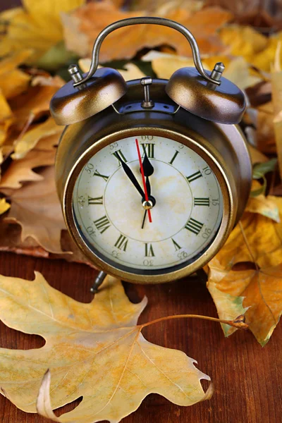 Alte Uhr auf Herbstblättern auf Holztisch in Großaufnahme — Stockfoto