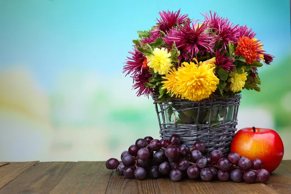 Gyönyörű virágok vázában fonott, a gyümölcsök, a fényes háttérben összetétele — Stock Fotó