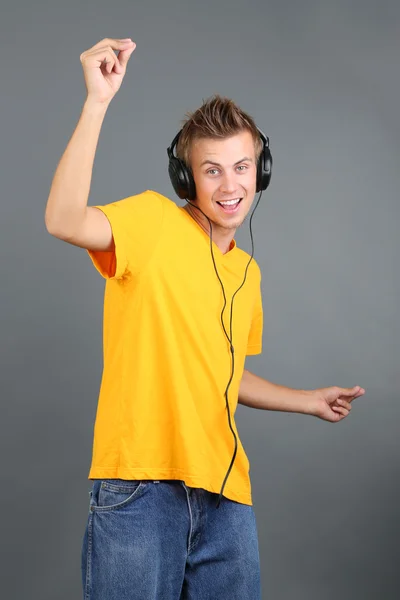 Handsome young man listening to music on grey background Stock Picture