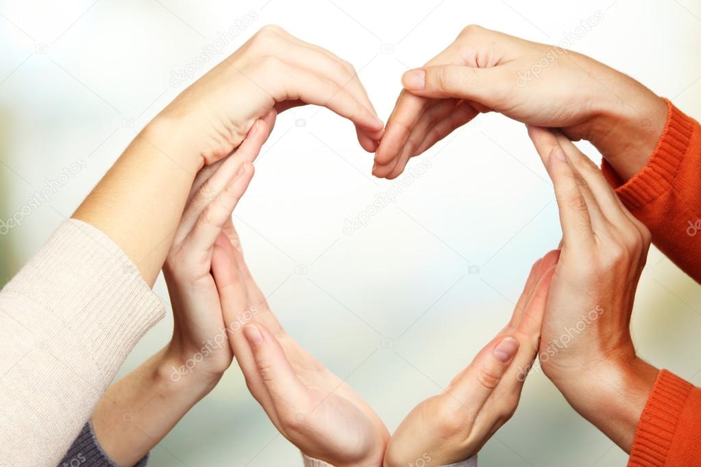 Human hands in heart shape on bright background