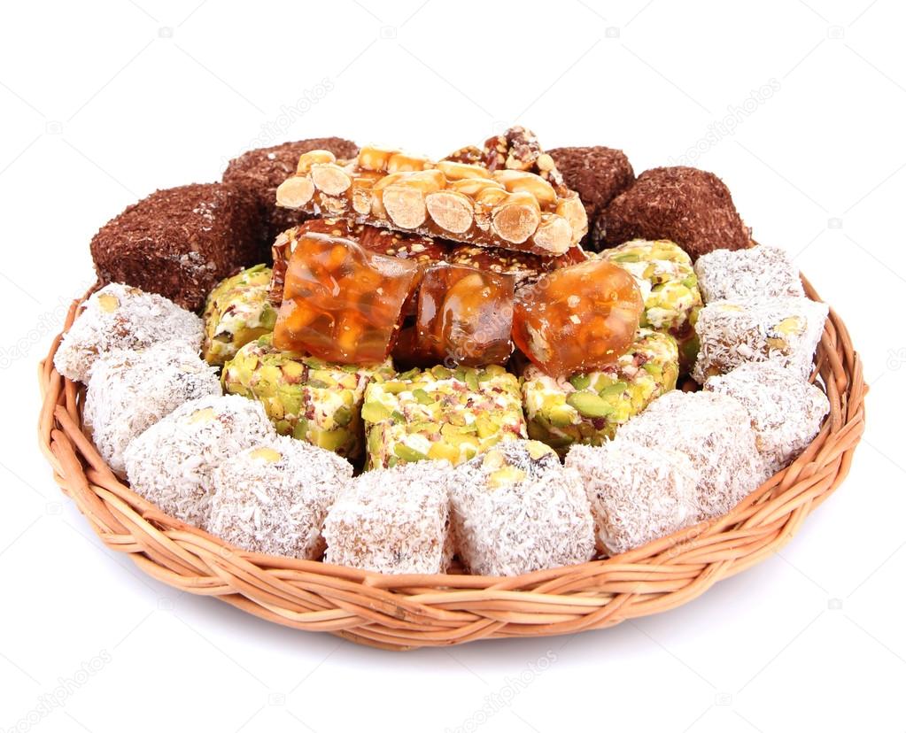 Tasty oriental sweets on wicker tray, isolated on white