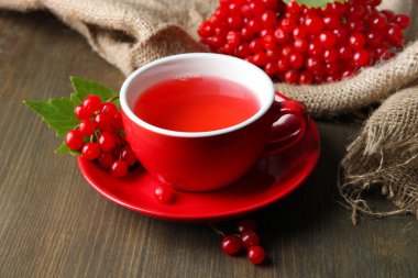 Bodegón con té de viburnum en servilleta de tela de saco, sobre fondo de madera