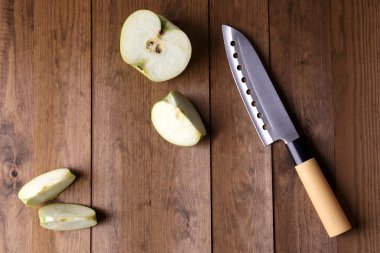 Mutfak bıçağı ve yeşil elma, ahşap arka planda.