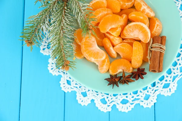 Tasty mandarine's slices on color plate on blue background — Stock Photo, Image