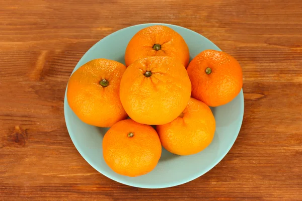Placa de cor mandarinas saborosas no fundo de madeira — Fotografia de Stock