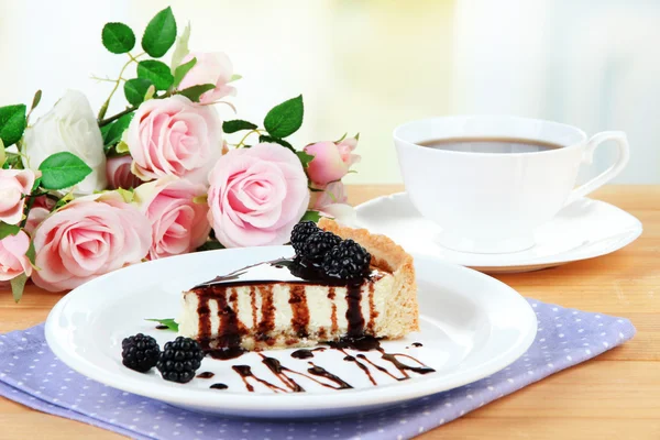 Slice of cheesecake with chocolate sauce and blackberry on plate, on wooden table, on bright background — Stock Photo, Image