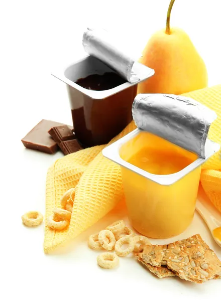 Sobremesas saborosas em copos de plástico abertos e frutas e flocos em guardanapo, isolados em branco — Fotografia de Stock