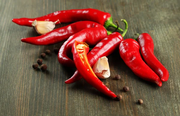 Red hot chili peppers and garlic, on wooden background — Stock Photo, Image