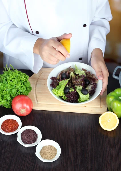 Cook hands squeezing lemon into salad — Stock Photo, Image