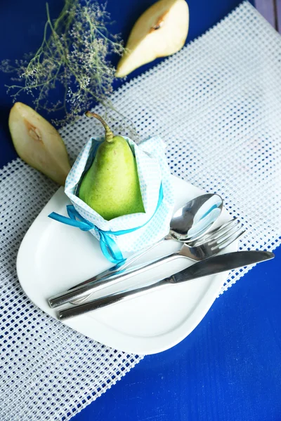 Pear in napkin on plate on wooden table close-up — Stock Photo, Image