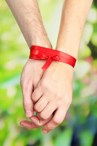 Mans and girls hands tied with ribbon on bright background — Stock Photo, Image