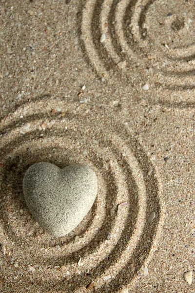 Gris piedra zen en forma de corazón, sobre fondo de arena — Foto de Stock