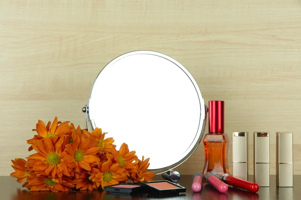 Specchio da tavolo rotondo con cosmetici e fiori sul tavolo su sfondo di legno — Foto Stock