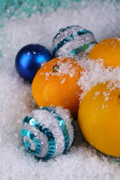 Tangerinas de Natal e brinquedos de Natal na mesa de madeira na neve — Fotografia de Stock