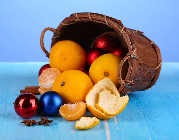 Tangerinas de Natal e brinquedos de Natal em cesta no fundo azul — Fotografia de Stock