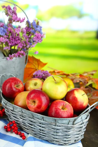 Сочные яблоки в корзине на столе на естественном фоне — стоковое фото