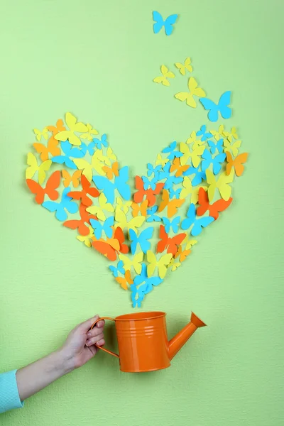 Papier vlinders vliegen uit gieter op groene muur achtergrond — Stockfoto