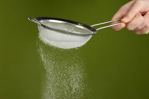 Sieve and powdered sugar on green background — Stock Photo, Image