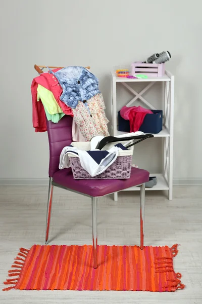 Heap of clothes on color chair, on gray background — Stock Photo, Image