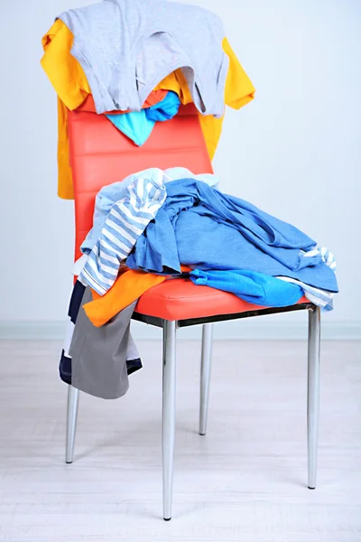 Hoop van kleren op kleur stoel, op grijze achtergrond — Stockfoto